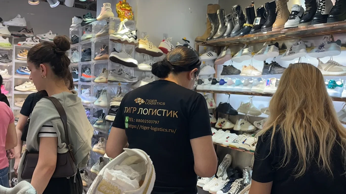 Сотрудница Tiger и покупатели выбирают обувь у поставщика
